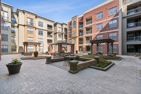 A courtyard with a brick floor and a building in the background.