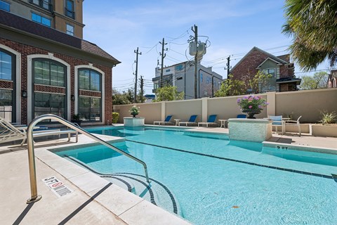 A swimming pool with a diving board and lounge chairs.