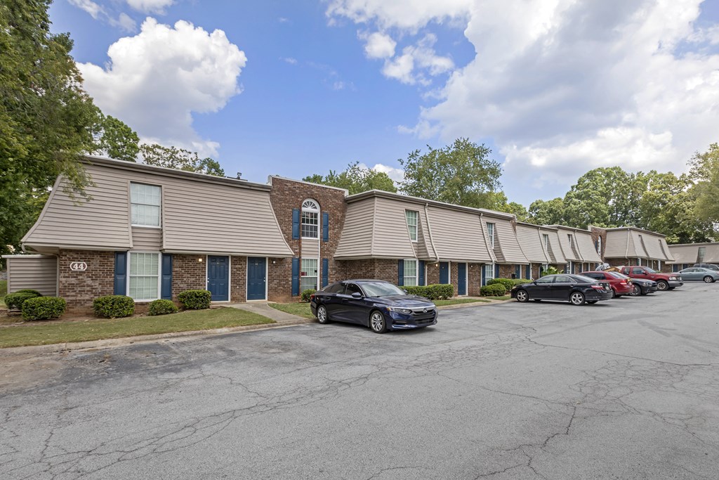 A parking lot with cars and a building with a brick facade.