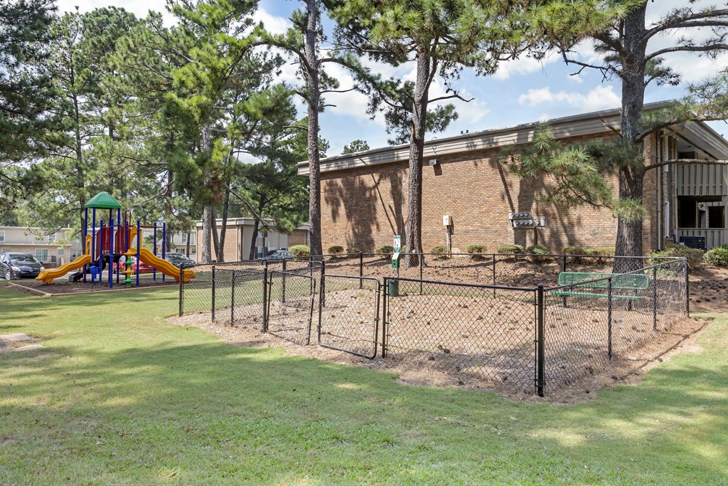 A playground with a slide and a fenced-in dirt area.