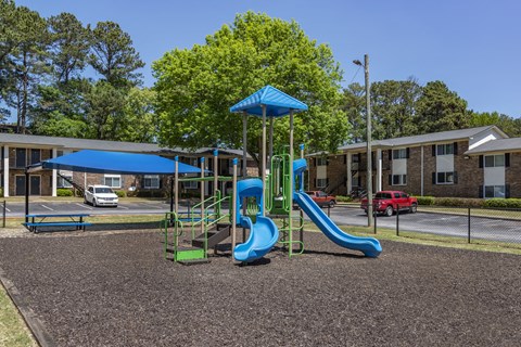 a playground with slides and a swing set in front of a building