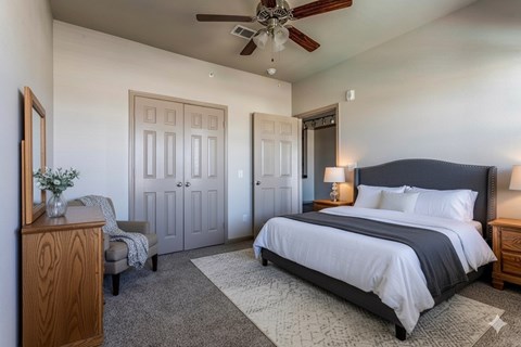 A bedroom with a large bed and a ceiling fan.