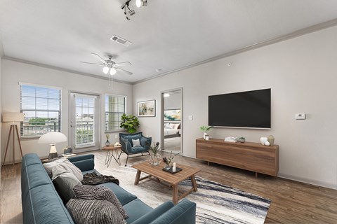 A living room with a blue couch and a television on the wall.