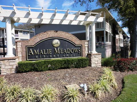 a picture of the amelia meadows clubhouse sign with a white pergola in front