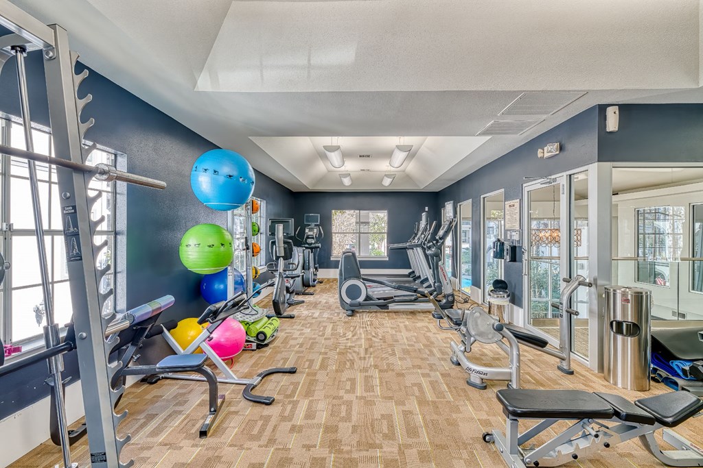 a gym with cardio equipment and weights on a wood floor