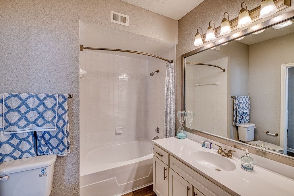 a bathroom with a white tub and a sink and a mirror