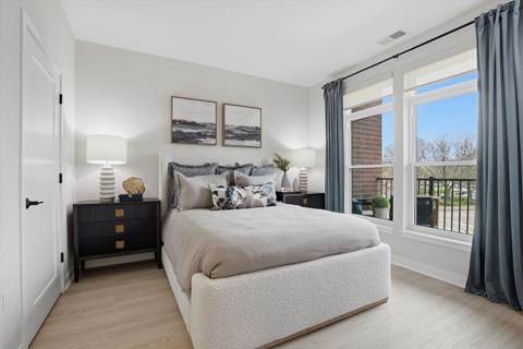 A bedroom with a large bed, a nightstand with a lamp, and pictures on the wall.