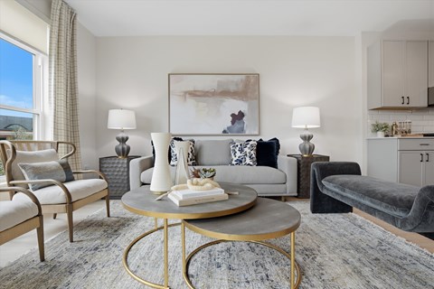 A living room with a grey sofa, a coffee table, and a painting on the wall.
