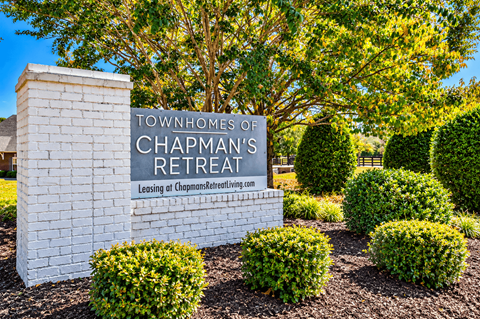 A sign for Chapman's Retreat stands in front of a tree.