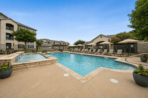 A swimming pool surrounded by a concrete patio and a black metal fence.