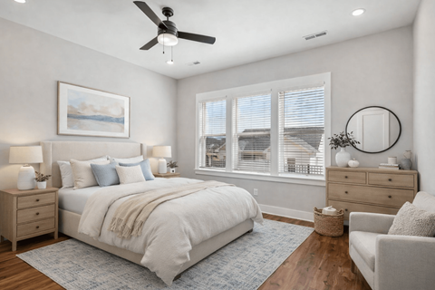 A bedroom with a large bed, a ceiling fan, and a painting on the wall.