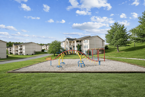 A playground with a slide and swings in front of apartment buildings.