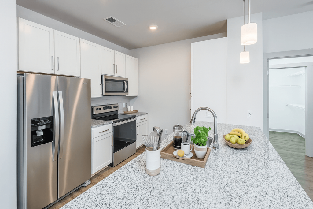 A kitchen with a refrigerator, microwave, oven, and sink.