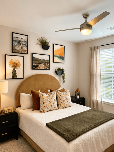 A bedroom with a bed, a ceiling fan, and pictures on the wall.