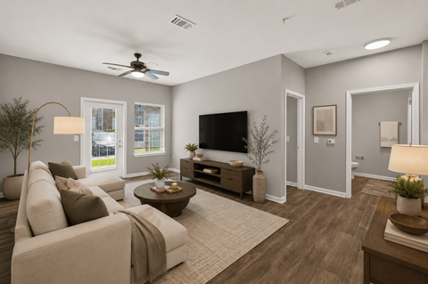 A living room with a couch, a coffee table, a television, and a ceiling fan.