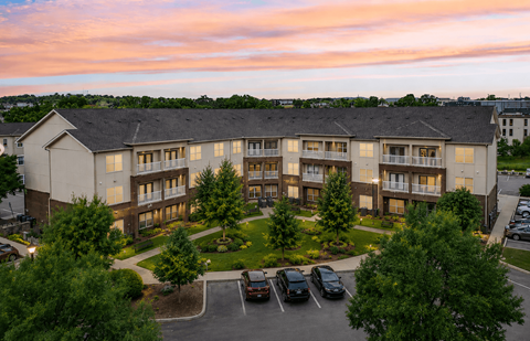A large apartment complex with a parking lot in front.