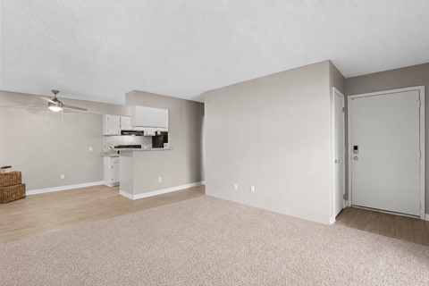A room with a ceiling fan and a kitchenette.