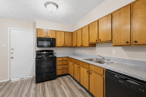A kitchen with wooden cabinets and black appliances.