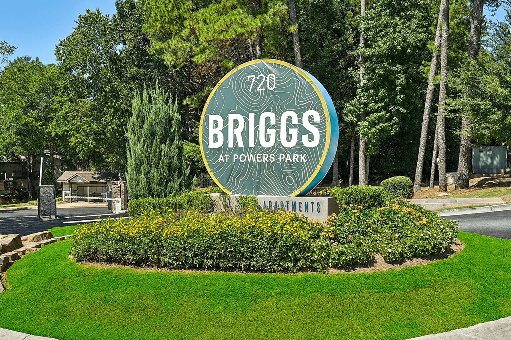 A sign for Briggs at Powers Park is surrounded by greenery.