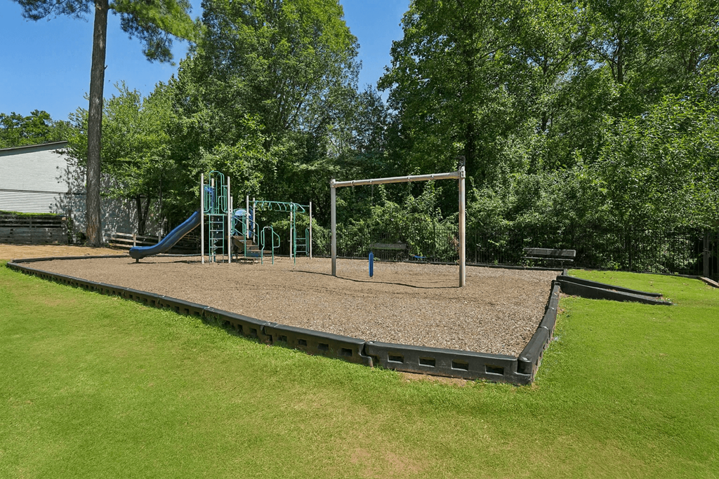 A playground with a slide, swings, and a seesaw.