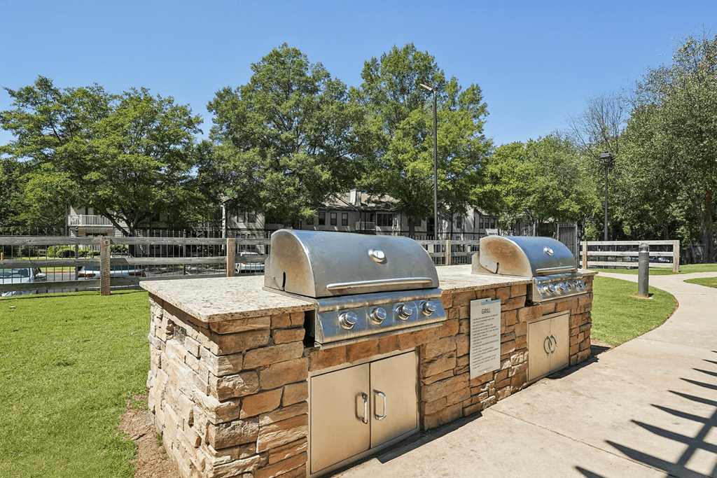A stone and metal structure with a dome on top is surrounded by a grassy area and trees.