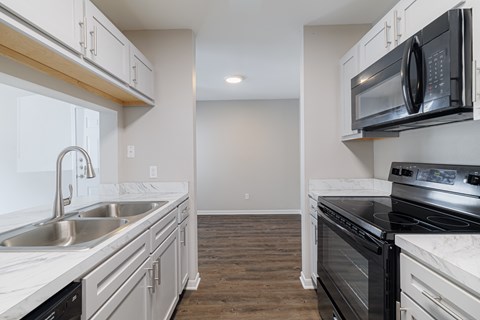 A kitchen with a black microwave oven mounted above a stove top oven.
