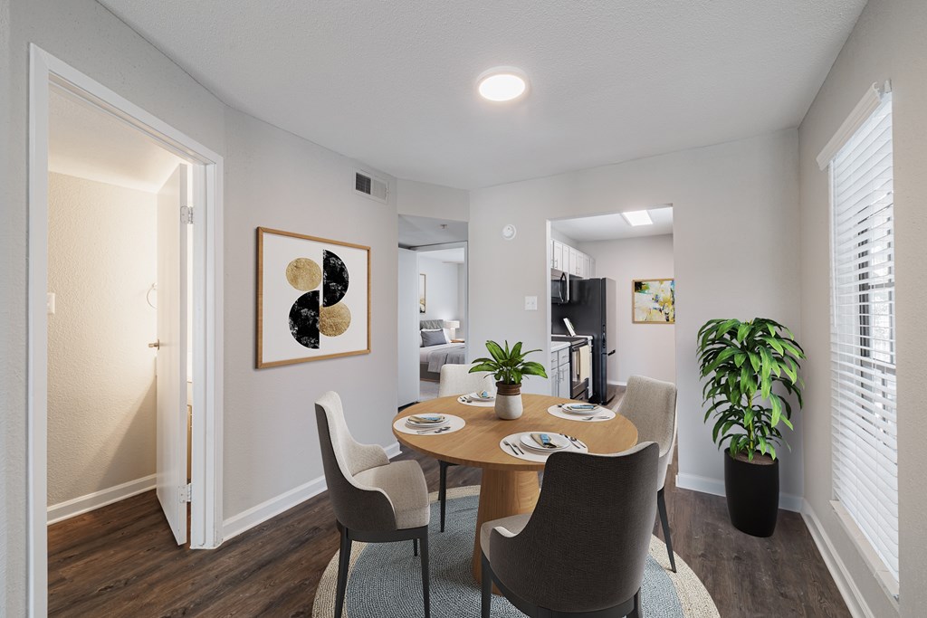 A dining room with a table set for two and a potted plant.