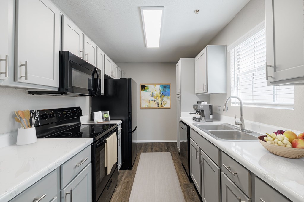A kitchen with black appliances and white cabinets.