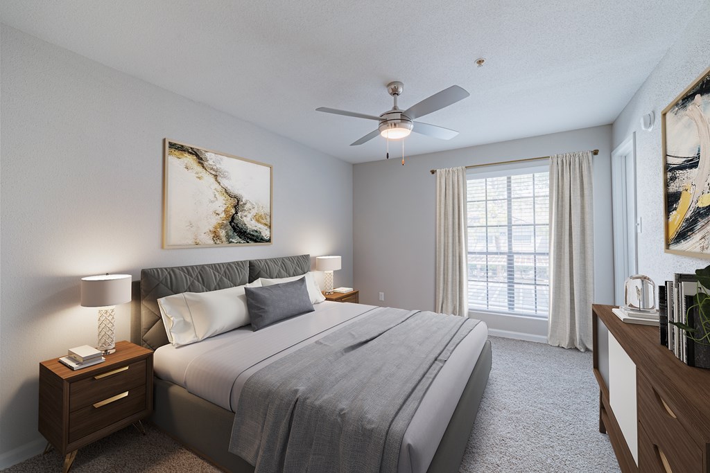 A bedroom with a large bed, a ceiling fan, and a painting on the wall.