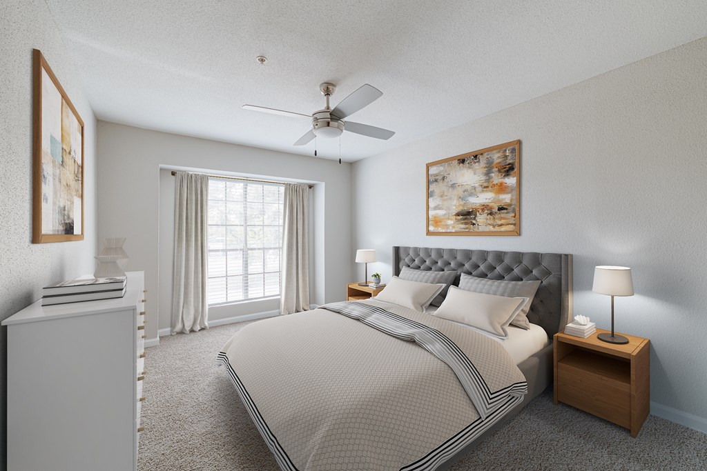 A bedroom with a large bed, a ceiling fan, and a window with curtains.