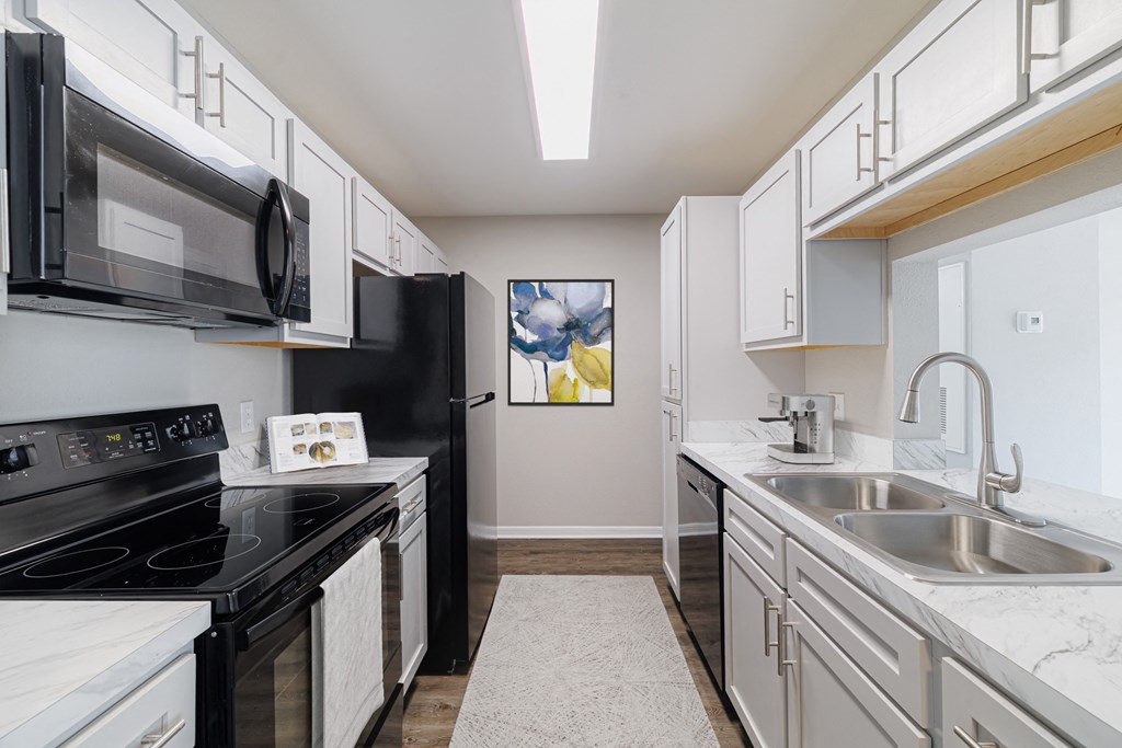 A kitchen with black appliances and white cabinets.