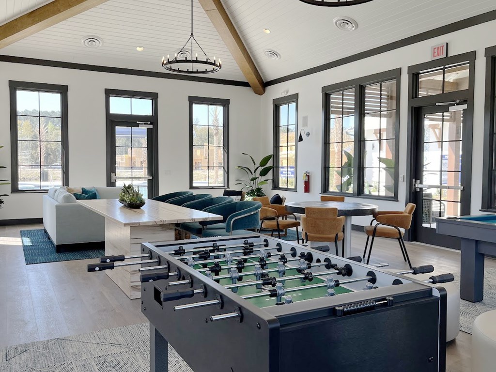 A foosball table is in the middle of a room with a couch and chairs.