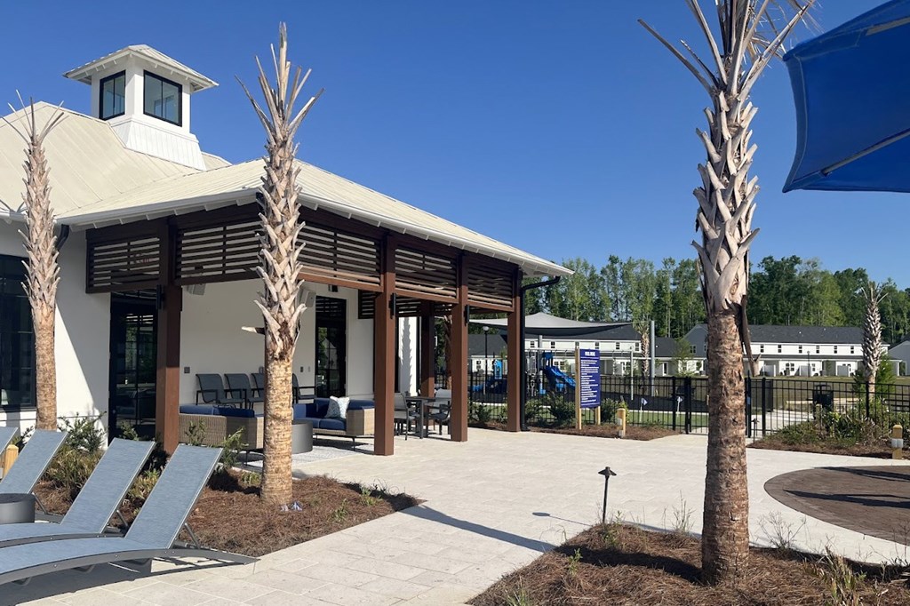 A building with a tower and a patio area with chairs and a tree.