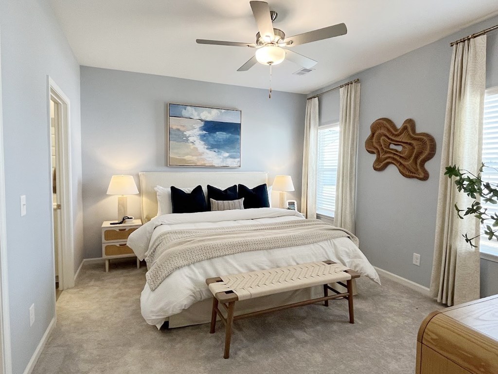 A bedroom with a large bed and a ceiling fan.