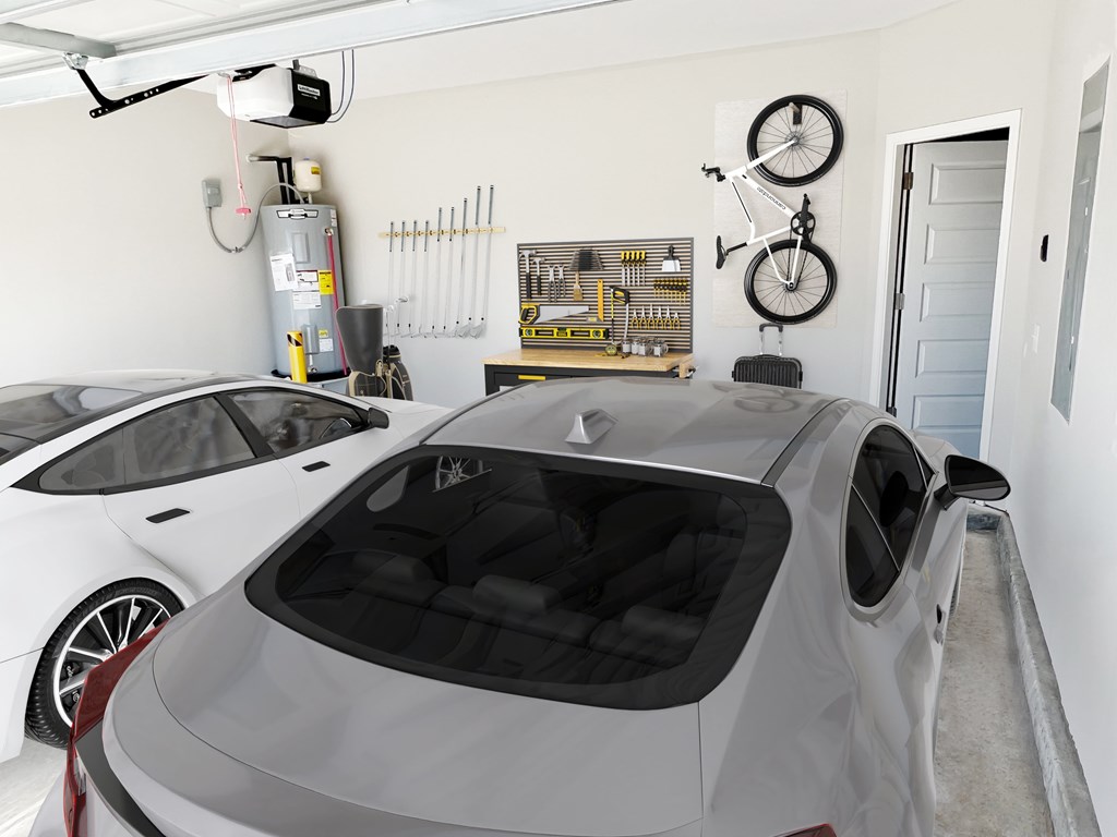 A grey car is parked in a garage with a white car behind it.