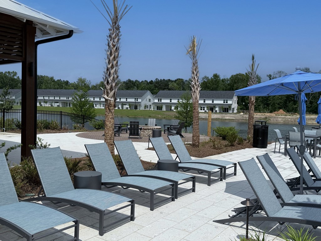 A patio with chairs and umbrellas overlooking a body of water.