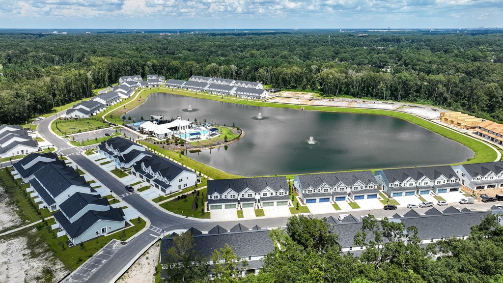 A bird's eye view of a residential area with a lake and houses.
