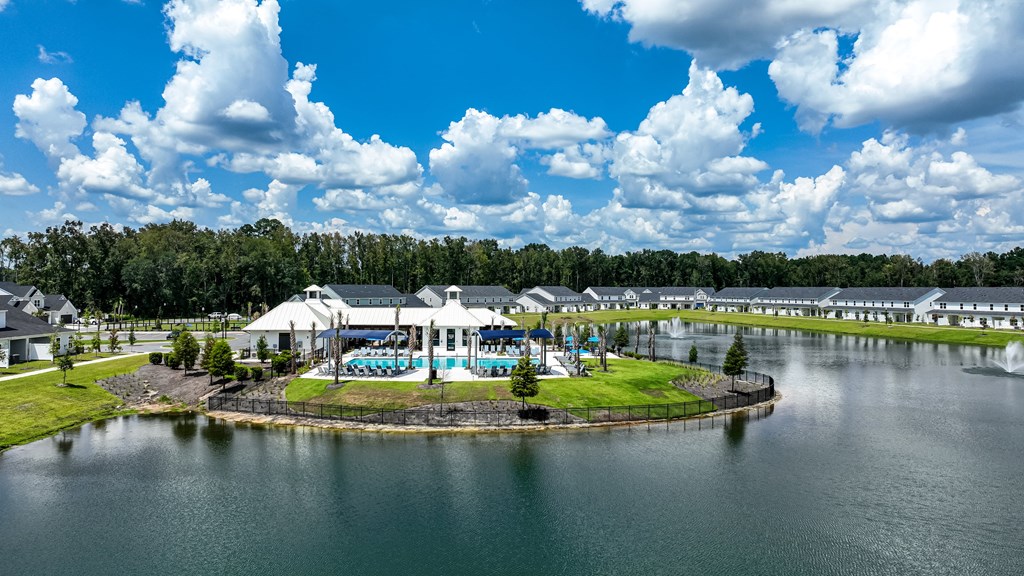 A large white building with a blue roof is surrounded by water and trees.