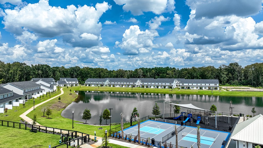 A large outdoor swimming pool with a slide and tennis courts.