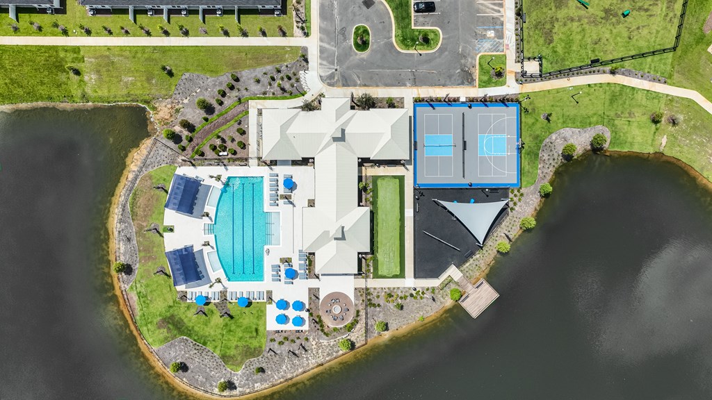 A bird's eye view of a resort with a swimming pool, tennis courts, and a tennis pavilion.