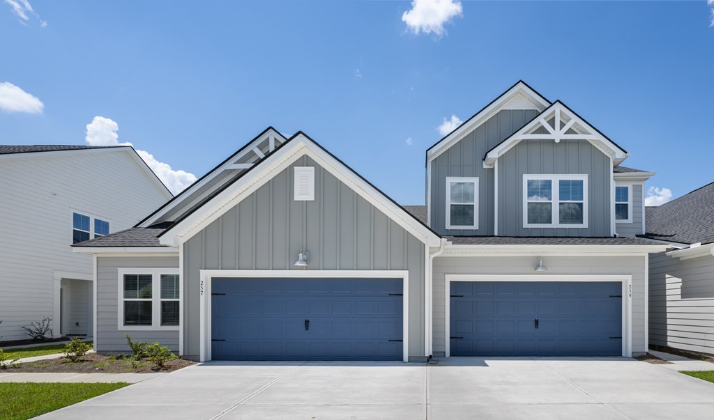 A modern house with a grey and white exterior and two garages.