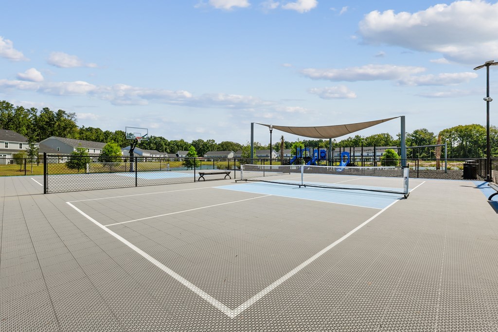 A tennis court with a net and a person standing in the middle.