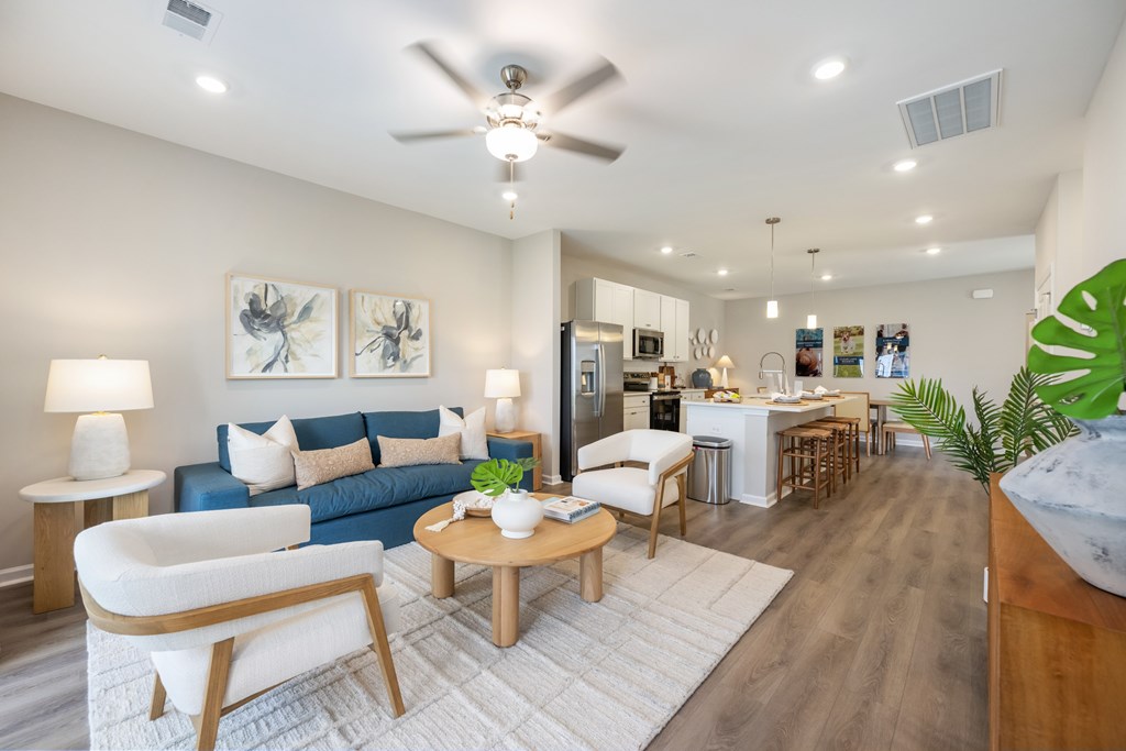 A living room with a blue couch, a white chair, and a wooden coffee table.