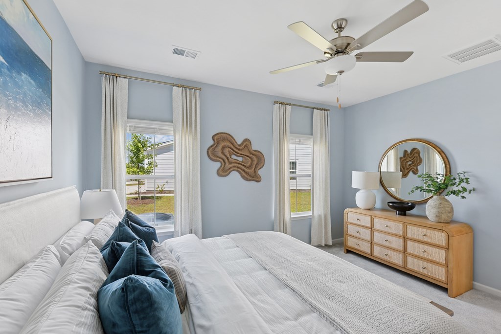 A bedroom with a large bed, a dresser, and a ceiling fan.