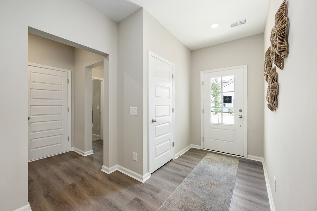 A hallway with a rug and a door on the right.