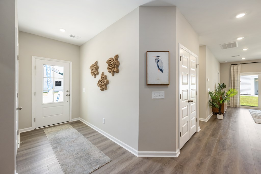 A hallway with a rug, a door, and a picture on the wall.