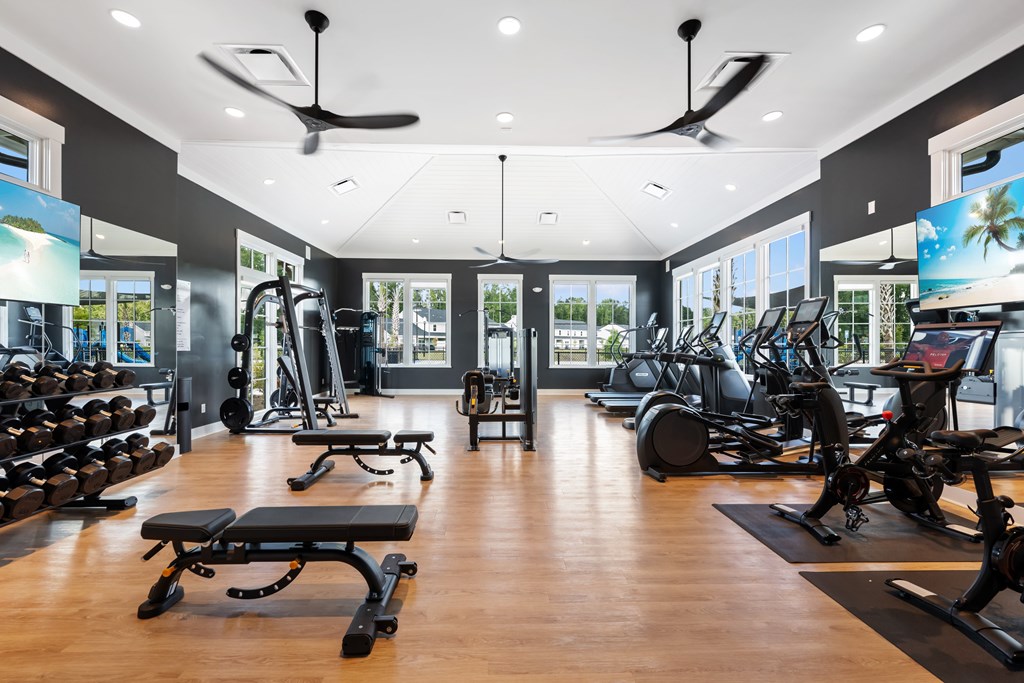 A gym with a variety of equipment including treadmills, weights, and exercise bikes.