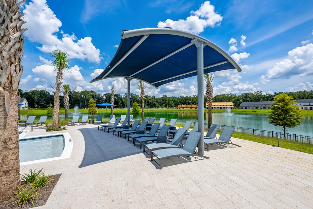A row of blue lounge chairs are arranged under a blue canopy.