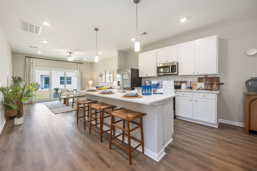 A kitchen with white cabinets and wooden floors.