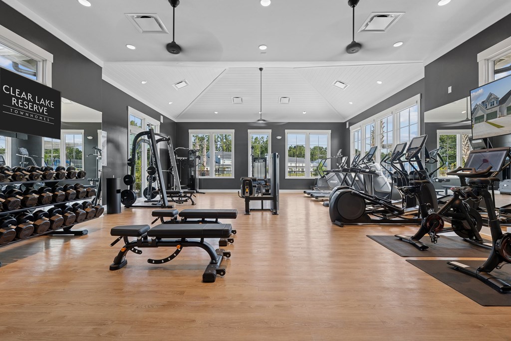 A gym with a variety of equipment including treadmills, weights, and exercise bikes.
